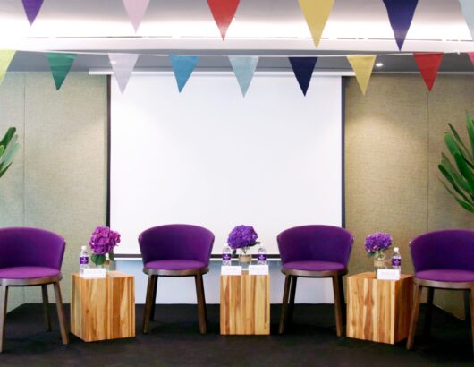 Four purple chairs on the stage of a Park Regis Singapore meeting room